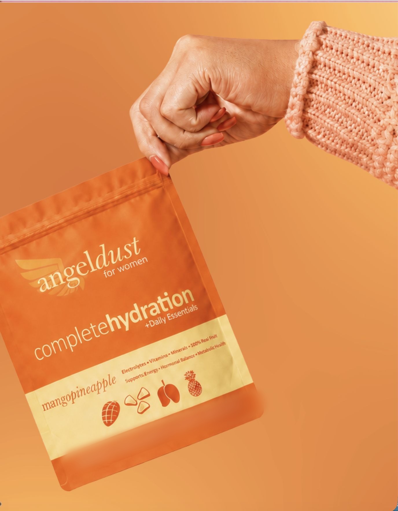 Hand holding a pouch of Angel Dust mango pineapple against an orange backdrop